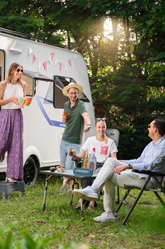 Vrienden genieten buiten bij een goed onderhouden tweedehands caravan van Adria
