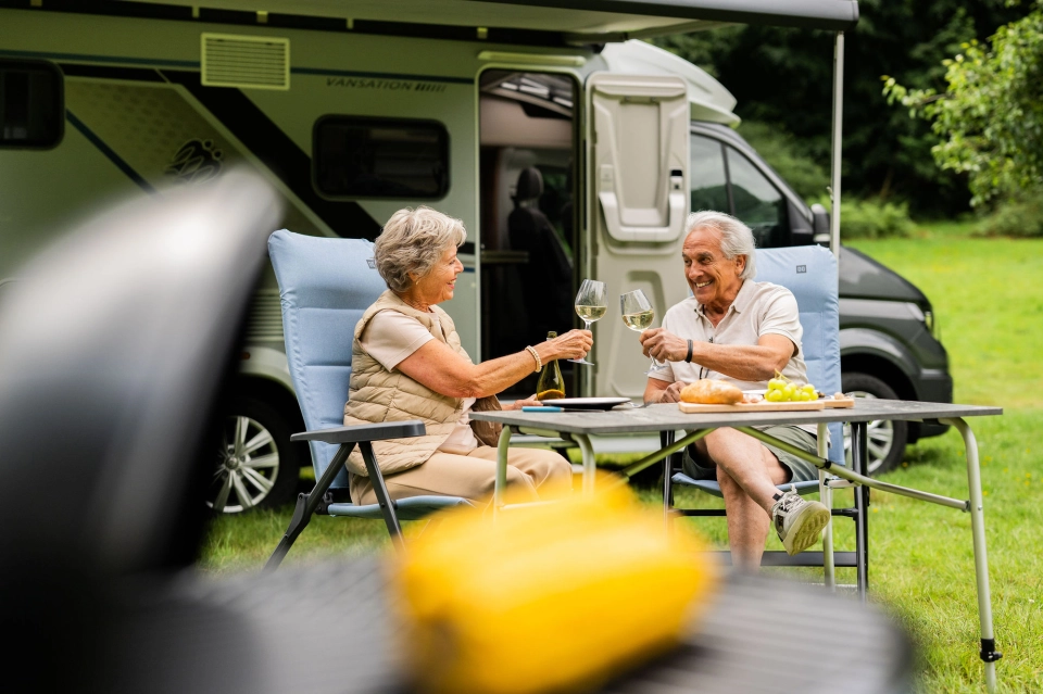 Stel geniet van een glas wijn buiten bij hun camper op de camping