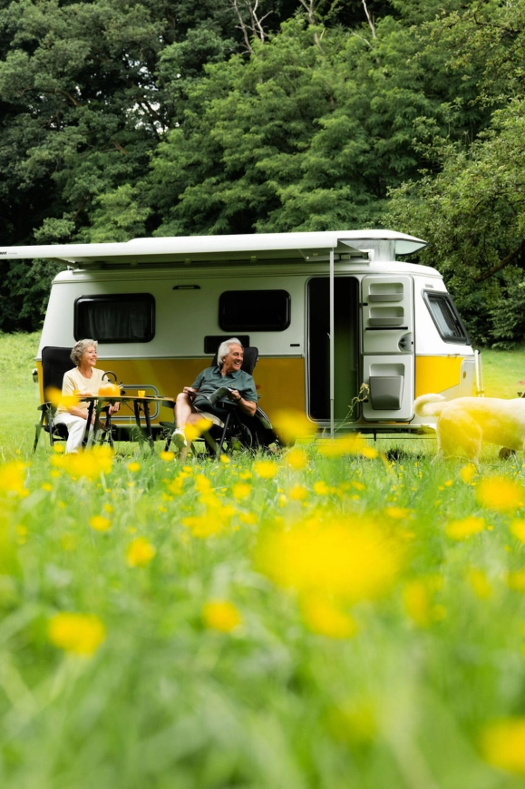 Stel geniet buiten bij een moderne caravan met luifel in een zomerse weide